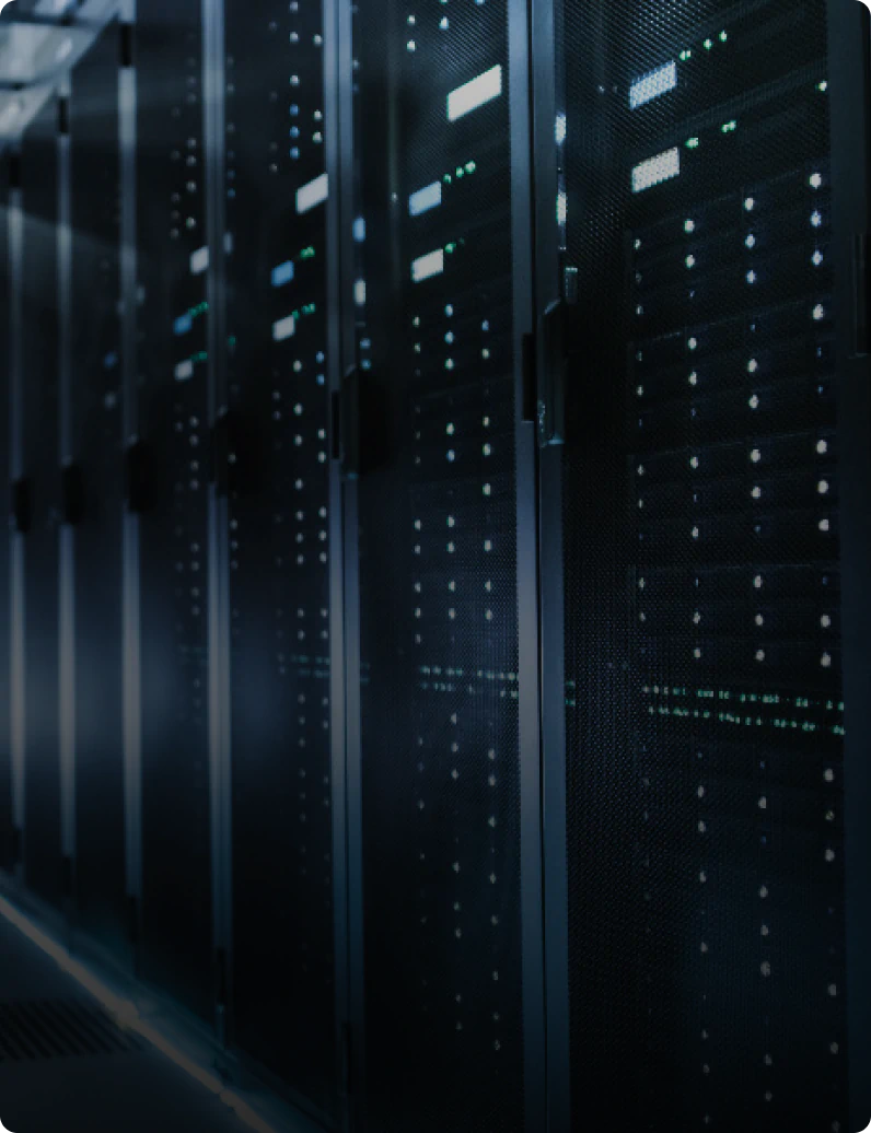 Darkened data center aisle lined with tall server racks, their mesh doors glowing with rows of green and white status LEDs.